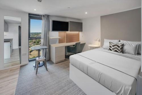 a hotel room with a bed and a desk and a television at Studio Apartments and Ensuite Bedrooms with Shared Kitchen at Chapter Ealing right next to North Acton Tube Station in London