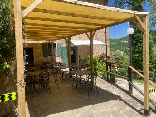 uma pérgola de madeira com mesas e cadeiras num pátio em Locanda dei Fienili del Campiaro em Grizzana