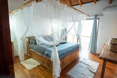a bed with a canopy in a room with a window at Sia Sente Beach estate in Inhambane