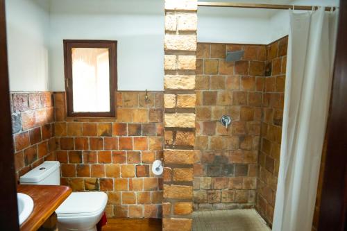 a bathroom with a brick shower with a toilet at Sia Sente Beach estate in Inhambane