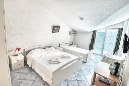 a white bedroom with a bed and a window at Sun Guest House in Budva