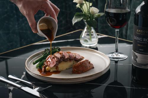a person drizzling sauce onto a plate of food at Hotel67 at Gleneagle in Killarney
