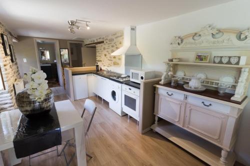 une cuisine avec des armoires blanches et une table et une salle à manger dans l'établissement Le Grenier de Margot, à Plaisance