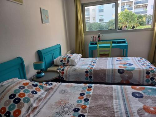 une chambre avec deux lits et une fenêtre dans l'établissement 3 pièces 62m2 balcon vue mer accès piscine tennis, à Hyères