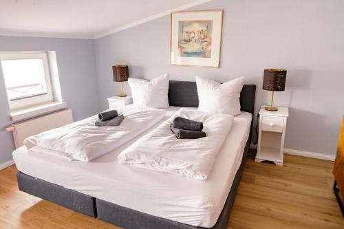 ein großes weißes Bett in einem Zimmer mit zwei Lampen in der Unterkunft Apartmenthaus Chrischanshof in Warnemünde