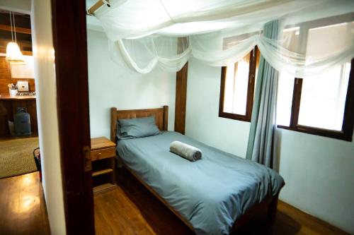 a small bedroom with a bed and two windows at Sia Sente Beach estate in Inhambane