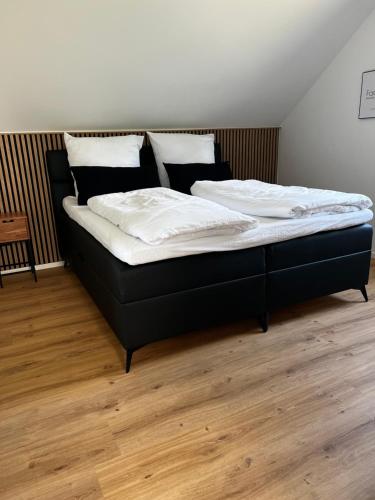 Ferienwohnung Weitblick في كوشيم: سرير أسود عليه أغطية ووسائد بيضاء