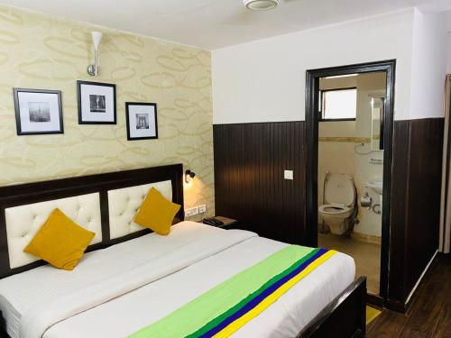 a bedroom with a large bed with yellow and green pillows at Hotel Fabstays-Safdarjung Enclave in New Delhi