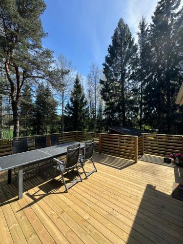 a wooden deck with a picnic table and chairs on it at Mysig stuga i Nävesta in Örebro