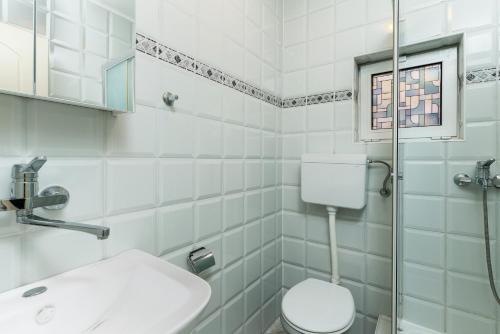 a white bathroom with a toilet and a sink at Sun Guest House in Budva