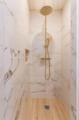 La salle de bains est pourvue d'une douche et de murs en marbre. dans l'établissement Appartement avec balcon - Cassis Centre, à Cassis