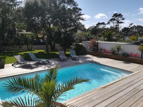 - une piscine dans une cour avec 2 chaises longues dans l'établissement Maison architecte neuve - piscine - 400m océan, à Labenne