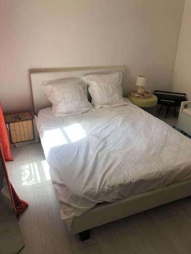 une chambre avec un lit avec des draps blancs et des oreillers dans l'établissement Upper West Side XVI Golden Triangle Cozy Flat, à Paris