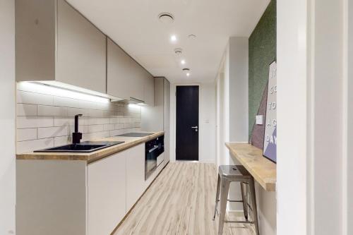 a kitchen with white cabinets and a sink and a counter at Chapter Ealing in North Acton in London