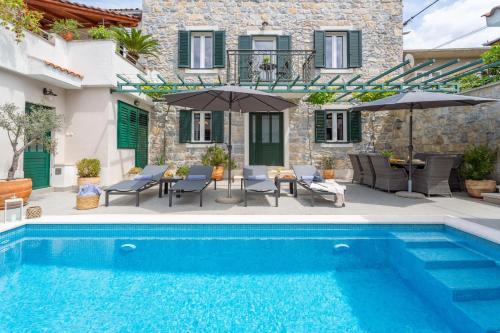 a villa with a swimming pool in front of a house at Villa Filipetti in Makarska center, 4 en-suite bedrooms charming stone house, heated private pool, 600m from beach in Makarska