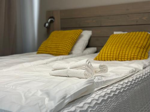 - 2 serviettes sur un lit blanc avec des oreillers jaunes dans l'établissement Joni Apartments, à Helsinki