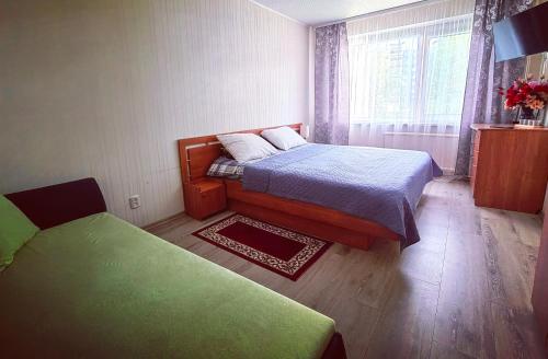 a small bedroom with two beds and a window at EMVIKA apartament in Šiauliai