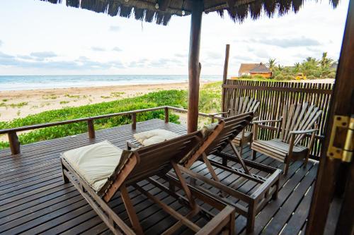 two chairs and a bed on a deck with the beach at Sia Sente Beach estate in Inhambane