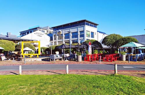 a building with tables and umbrellas on the side of a road at Apartment at Hermanus Waterfront in Hermanus