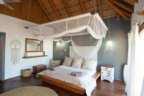 a bedroom with a white bed with a canopy at Sia Sente Beach estate in Inhambane
