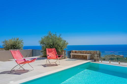 two red chairs sitting next to a swimming pool at Patio Villa Lydia in Stoupa