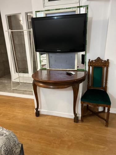 a tv on a table with a chair next to a window at Romana Boutique in Bucharest