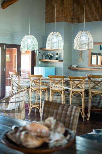 a dining room with a table and chairs and pendant lights at Sia Sente Beach estate in Inhambane