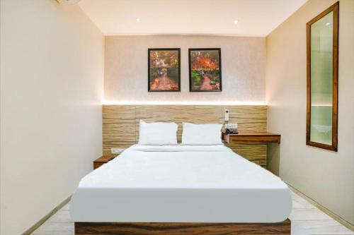 New Dream Residency By Glitz Hotels في مومباي: غرفة نوم بسرير ابيض كبير وصورتين على الحائط