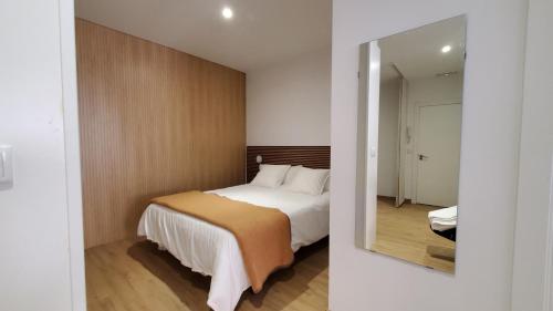 Habitación de hotel con cama y espejo en BAHíA APARTAMENTOS TURÍSTICOS, en Foz
