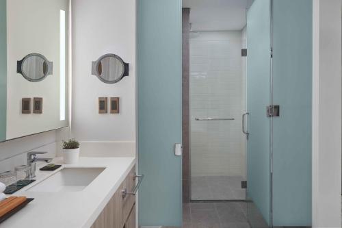 a white bathroom with a shower and a sink at Lanson Place Mall of Asia Manila in Manila