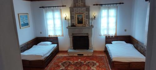 2 Betten in einem Zimmer mit Kamin und Fenstern in der Unterkunft Grevena country House 