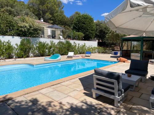 a swimming pool with two chairs and an umbrella at Les Iris Villa Piscine chauffée 6 pers in Moissac-Bellevue
