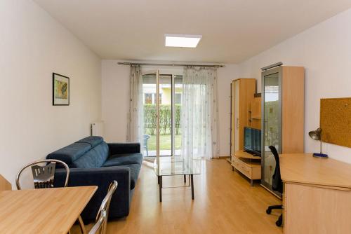 uma sala de estar com um sofá azul e uma televisão em Appartement Graz - Ihr erstklassiges Zuhause fernab von Zuhause em Graz
