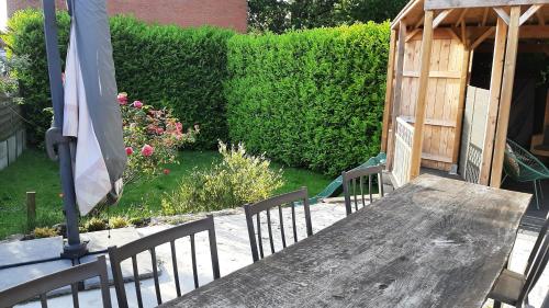 a wooden table and chairs in a garden at Calypso Massimo in Heuvelland