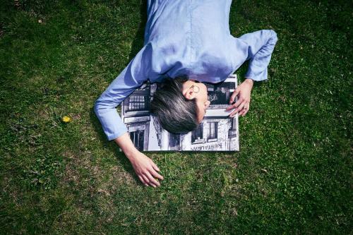 a man laying on the grass with a magazine at Hotel KÜGLERHOF in Tirolo