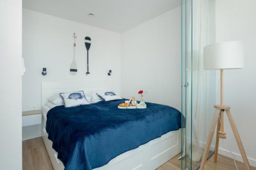 a bedroom with a bed with a blue blanket at Bulwar Zachodzącego Słońca Apartament z Widokiem na Morze by Noclegi Renters in Darłówko