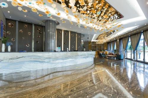 a lobby of a hotel with a bar and chandeliers at MIZPARTON HOTEL - Heshan Xinhua City Store in Jiangmen