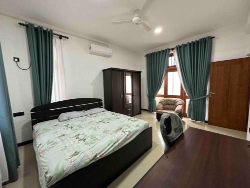 a bedroom with a bed and a chair in it at Beauty World Villa - Gampaha in Gampaha