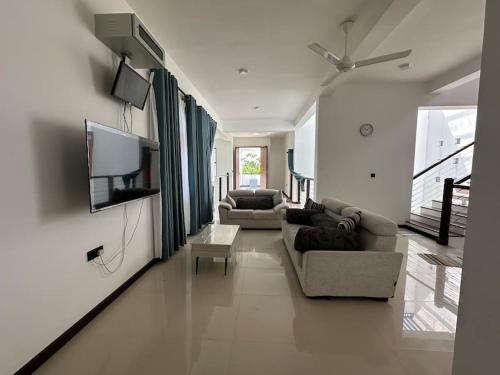 sala de estar con 2 sofás y TV de pantalla plana en Beauty World Villa - Gampaha, en Gampaha