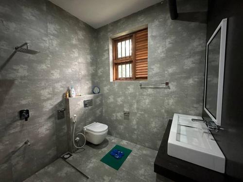 a bathroom with a toilet and a sink and a window at Beauty World Villa - Gampaha in Gampaha