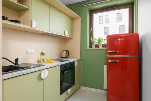 a red refrigerator in a kitchen with green walls at Student Depot Lublin Apartamenty in Lublin