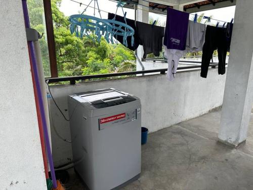a trash can sitting next to a window with clothes drying at Beauty World Villa - Gampaha in Gampaha
