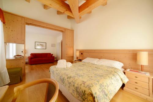 a bedroom with a bed and a red couch at Hotel Paganella, Tradition In Hospitality in Fai della Paganella