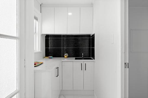 a white kitchen with a sink and a window at Auckland airport holiday home in Auckland