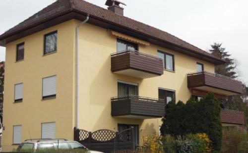een geel gebouw met balkons en een auto voor de deur bij Ferienwohnung Romantic in Bad Kissingen