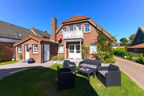 ein Haus mit einem Garten mit Stühlen und einem Tisch in der Unterkunft Ferienwohnungen Kapitäns Kajüte in Bensersiel