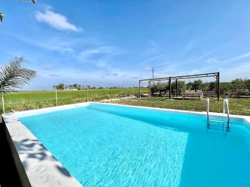 a blue swimming pool with a field in the background at Villa Delta in L'Eucaliptus