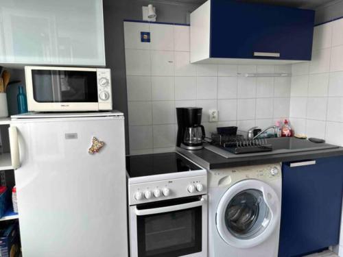 une cuisine avec un lave-linge et un micro-ondes dans l'établissement Appartement proche centre, à Dinard