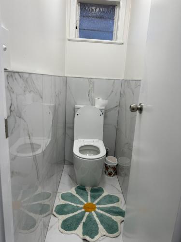 a bathroom with a toilet with a flower rug at Auckland airport holiday home in Auckland