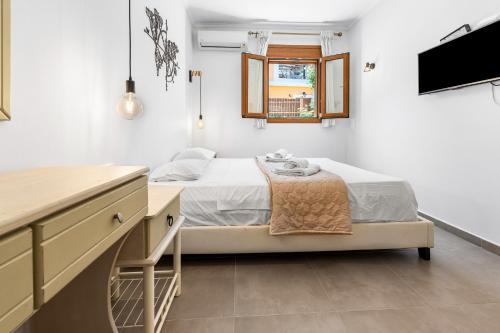 a bedroom with a bed and a desk and a television at Villa Semipuella in Agios Nikitas